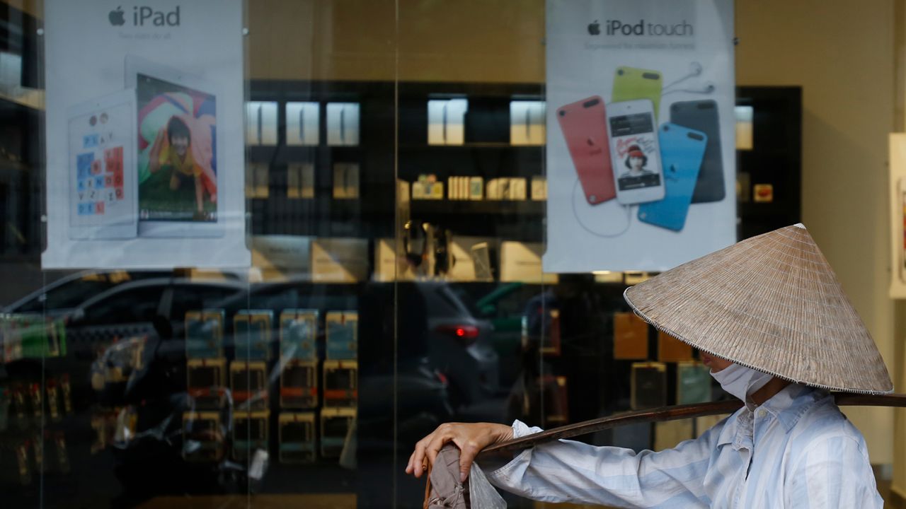 A fruit vendor walking past an Apple store in Hanoi in 2014. 