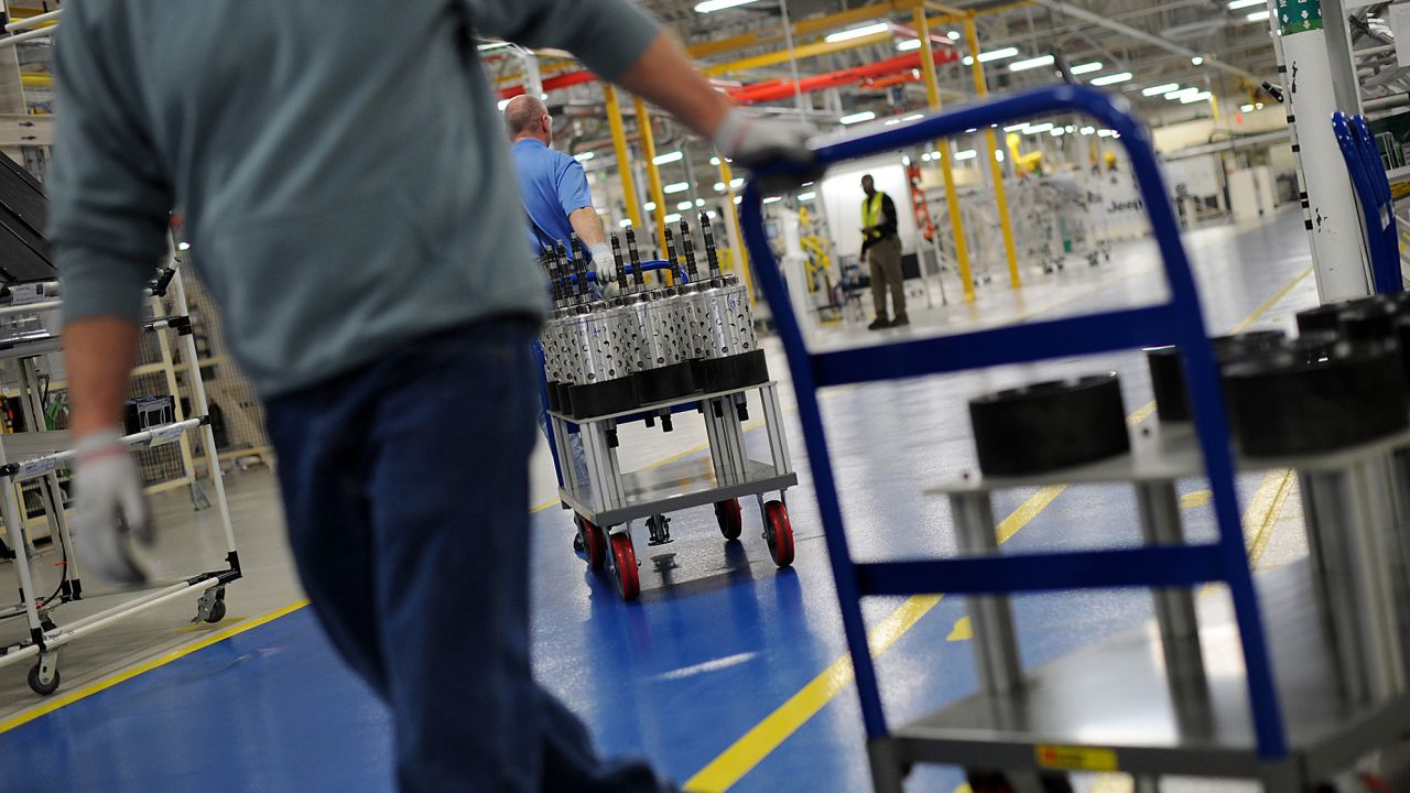 Employees pull carts carrying transmission parts a transmission plant in Kokomo.