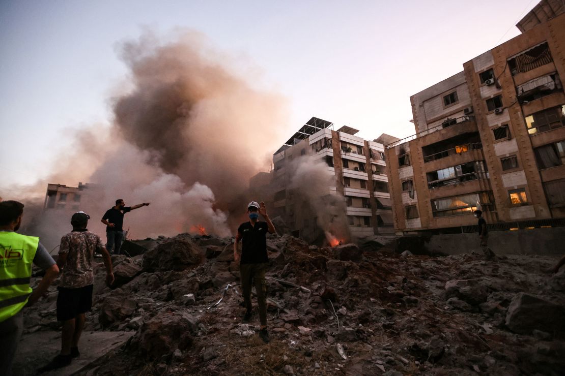 People and rescuers stand amid the rubble of a building destroyed in an Israeli air strike in the Haret Hreik neighbourhood of Beirut's southern suburbs on September 27, 2024.